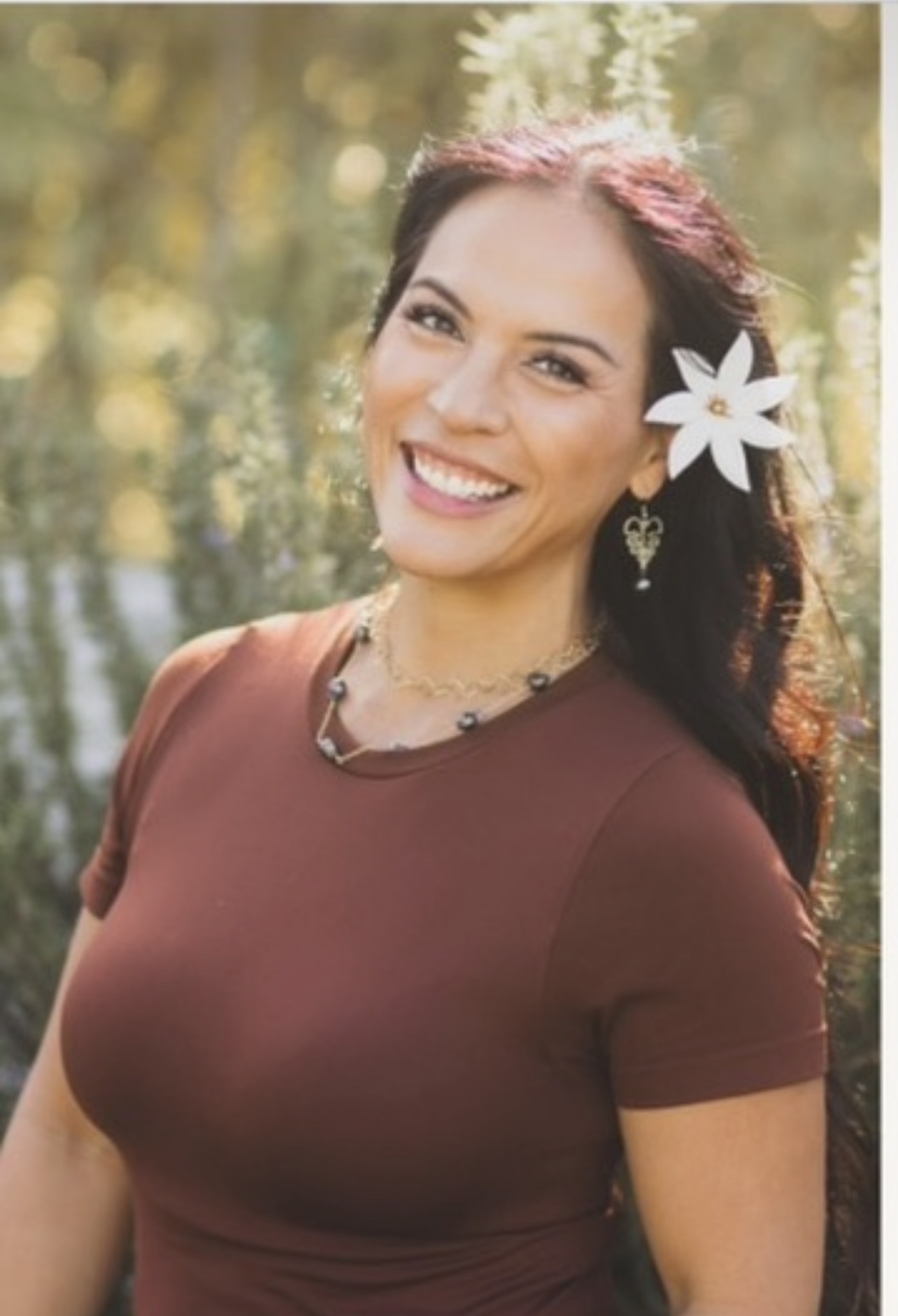 Misty smiling warmly outdoors with a flower in her hair, natural golden-hour light