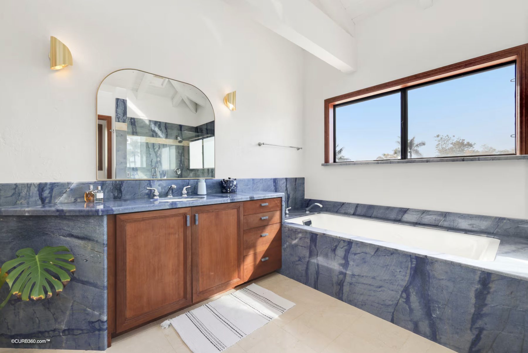 A bathroom with blue stone counters, a soaking tub and a window