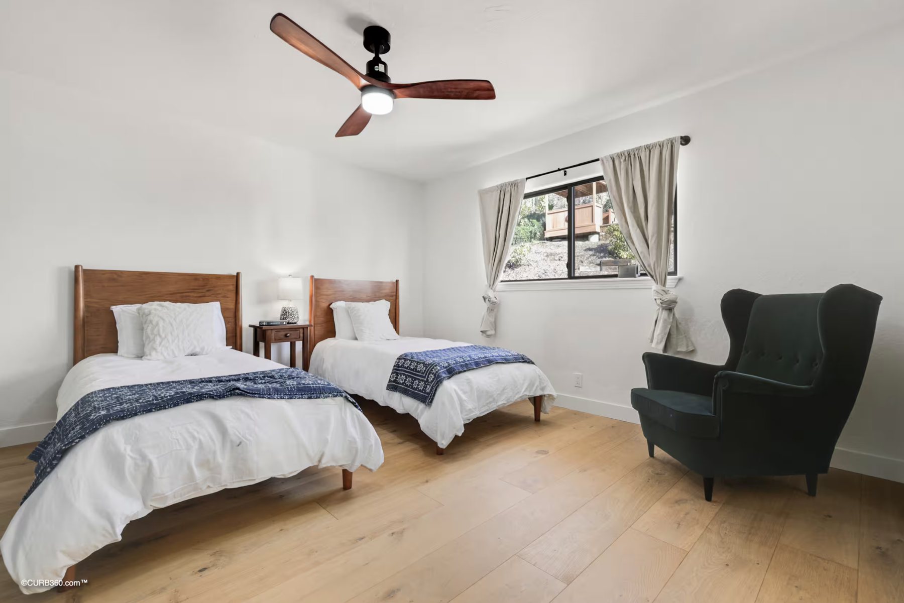A bedroom with two twin beds, an armchair and a window