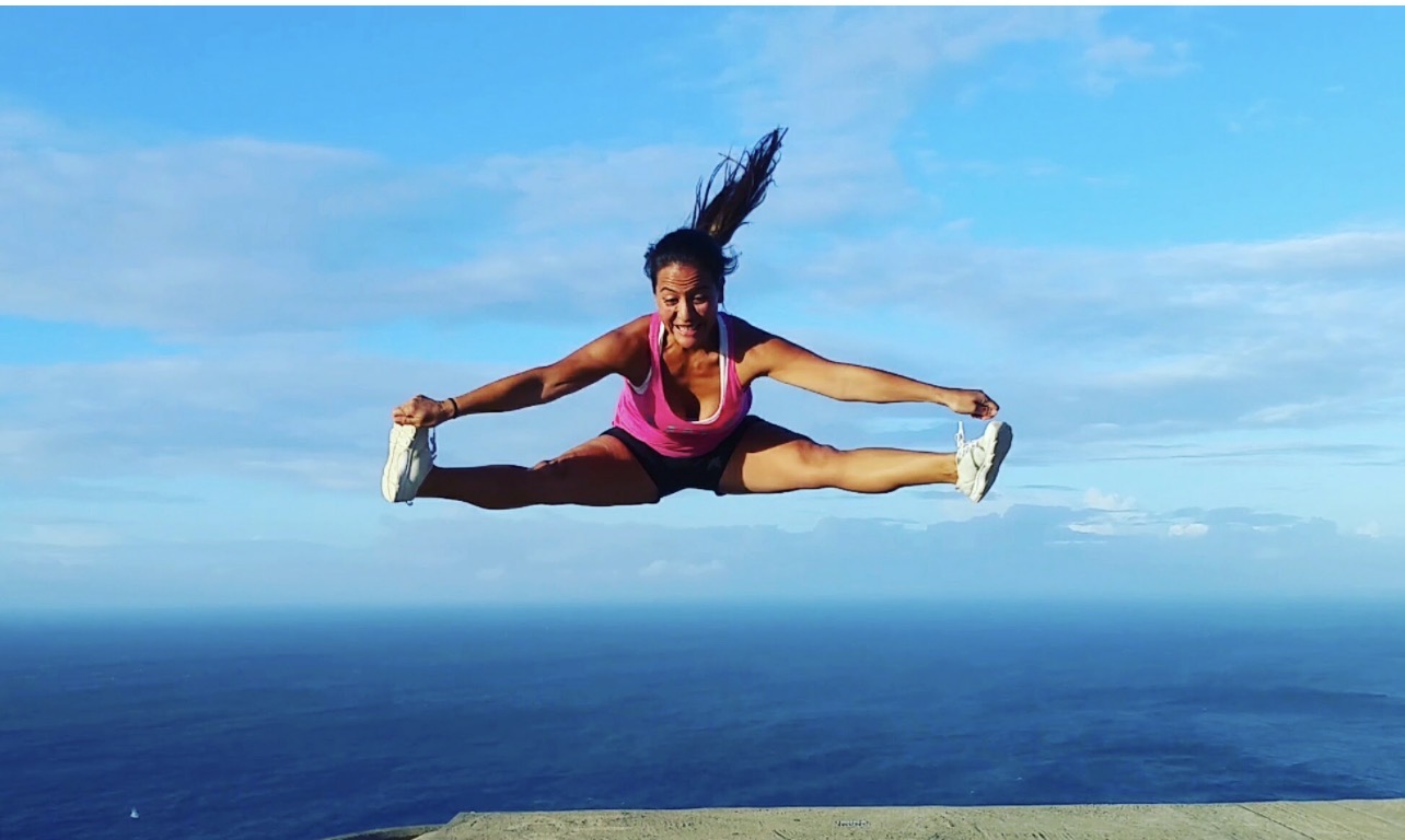Misty airborne in a jump split above the Maui coastline, ocean in the background